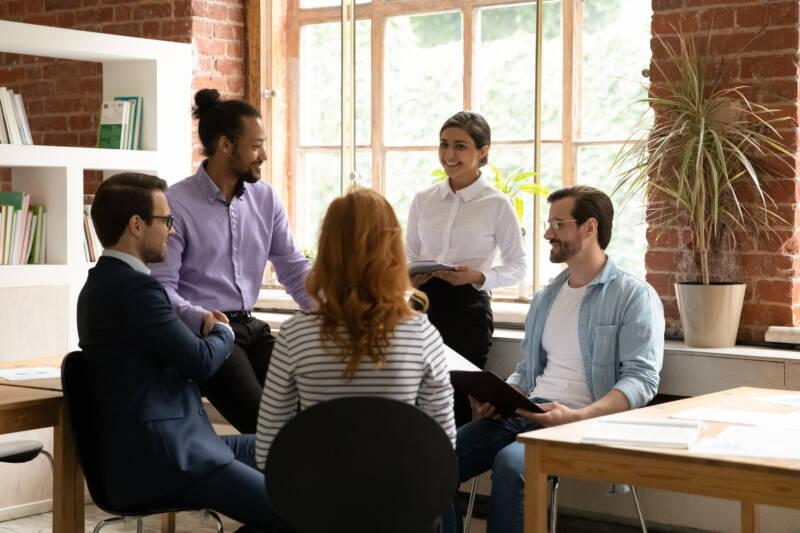 People sitting closely together, smiling, having a conversation, in a well-lit office space